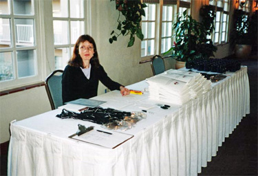 Sign-in desk with participant sign-in sheet, name badges, participant notebooks, and participant mugs at Bandelier National Park Greening Charrette.